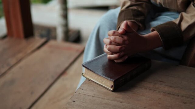 A young woman sits praying to God with her Bible, asking for a peaceful healing in her life healed by love and His holy word