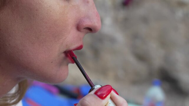 Lipstick beauty makeup woman applying bright red liquid cosmetic to her lips with an applicator in close profile view