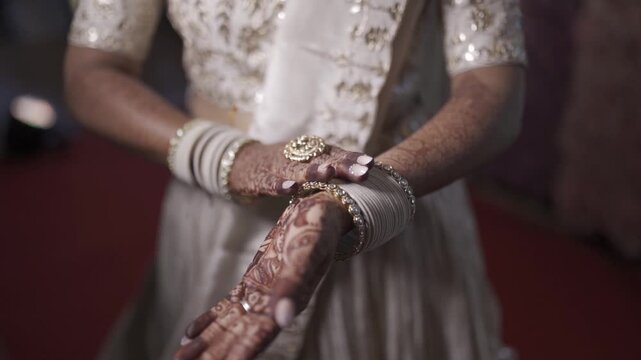 Indian bride showing intricate henna hands and traditional jewelry at wedding ceremony