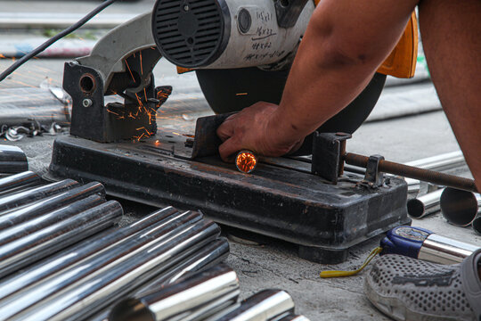 Industrial Worker Using Precision Cutting Machine on Metal Pipes with Safety Protection Equipment
