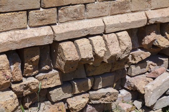 Weathered stone wall stands strong under sun's gaze