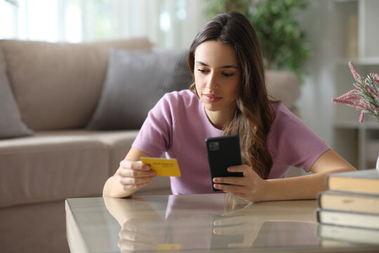 Serious woman shopping online using card and phone