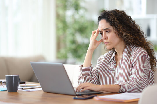 Worried adult teleworker using laptop working at home
