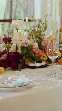 Vertical video. Wedding table decoration with pink flowers, taper candles, glassware and plates.