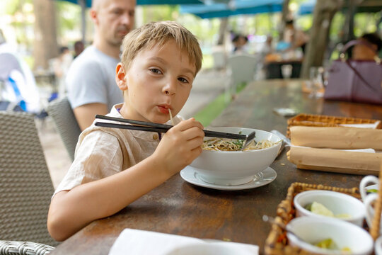 Child, kid boy, eating traditional Pho Bo soup in vietnam, kid trying street food in Ho Chi Minh