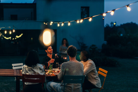 Friends gathering for evening garden dinner party celebrating