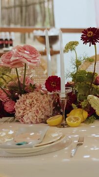 Vertical video. Wedding floral centerpiece with candles and table setting. Wedding decor or party.