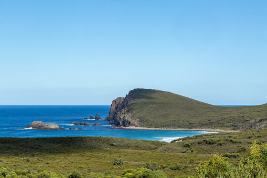 Distant view of a small rocky coastal bay with headland in distance.