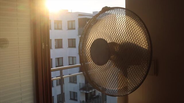 Electric fan cooling a room during an extreme summer heatwave at sunrise.