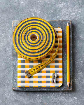Yellow Measuring Tape and Pencil on Checkered Notebook