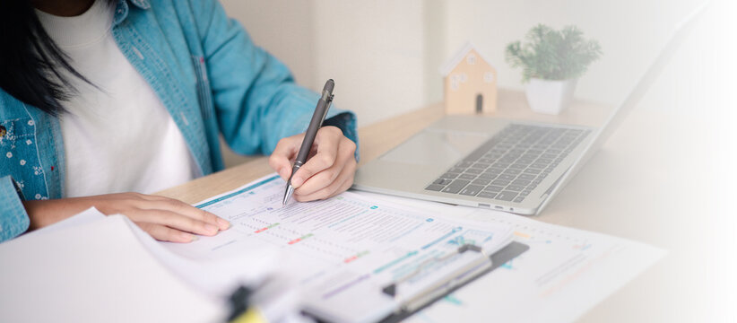 Business professional reviewing performance reports and auditing stack of documents at office desk. Concept of corporate audit, compliance check, data analysis, and financial reporting process.