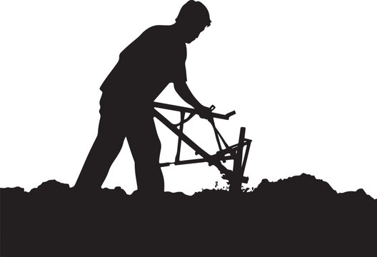 Silhouette of a man plowing soil with a manual plow