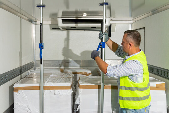 Worker adjusting temperature in refrigerated cargo box