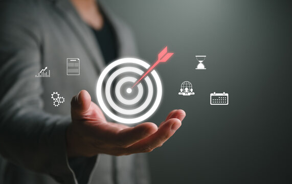 Business target concept with glowing bullseye and arrow above an open hand, symbolizing goal achievement, strategic planning, KPI performance, marketing success, leadership, and corporate growth.