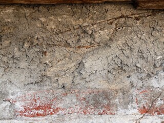 Grungy weathered wall texture with rough concrete, crumbling plaster, and exposed red brick. Abstract background. © suciramadhani