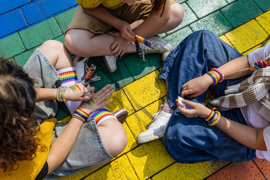 Friends paint rainbow flag on hand during pride parade
