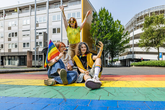 Friends taking a selfie at a colorful pride parade on a city street