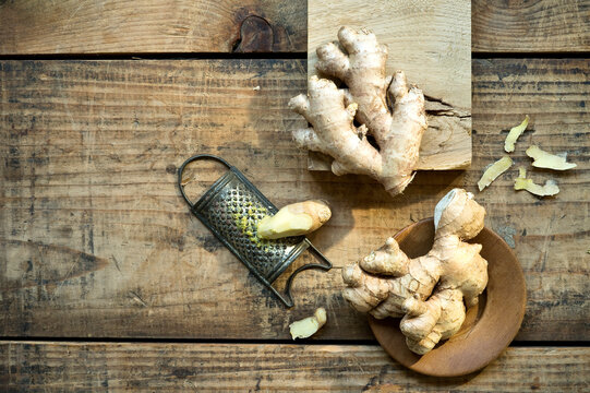 Ginger roots and old grater lying on wooden surface
