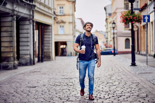 Traveler with backpack and coffee admiring the architecture