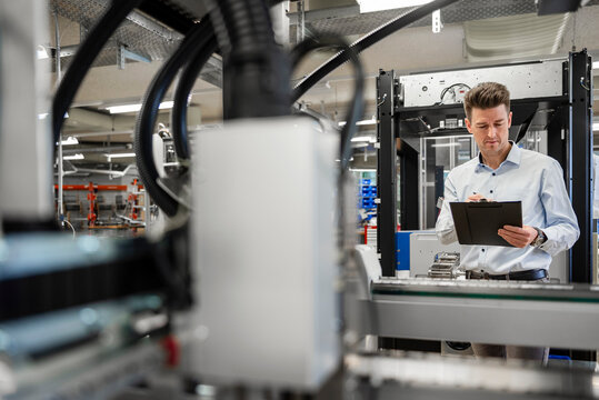 Engineer checking machinery with tablet in production hall