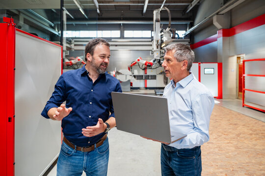 Engineer and manager discussing with laptop in factory