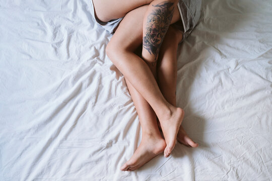 Lesbian couple legs lying on bed at home