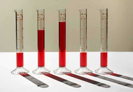 Measuring cylinders with red liquid forming a bar chart