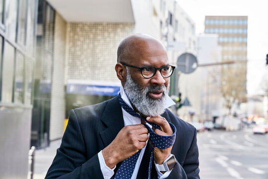 Mature businessman tying tie in the street