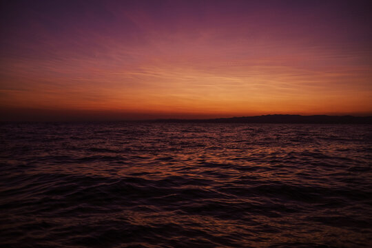 Calm sea water rippling under a colorful sunset sky