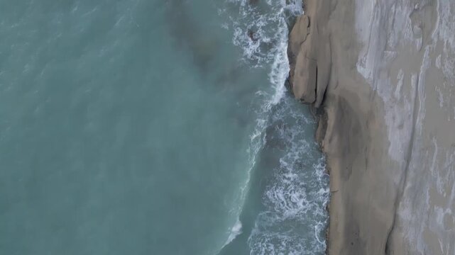 Wind erosion rock cliff mountain in coastal landscape of ocean sea wave dynamic rugged steep environment vertical face tide weather abrasion natural Iran adventure aerial geology limestone Oman Muscat