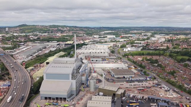 Aerial drone footage of a modern waste-to-energy facility located beside the M5 motorway in the West Midlands, England. Industrial infrastructure surrounded by residential neighbourhoods, warehouses