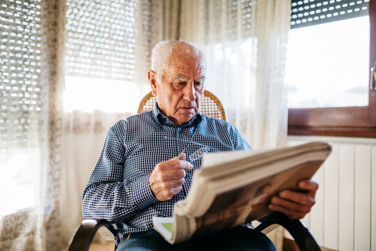 Senior man reading newspaper at home