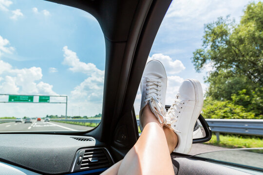 Italy, feet of woman leaning out of car window