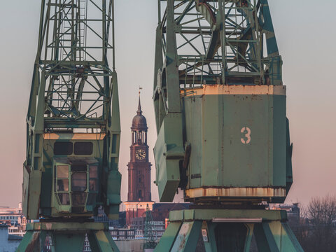 Germany, Hamburg, Saint Michaels Church tower seen between two industrial cranes