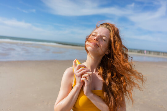 Smiling woman applying suntan lotion at beach on summer vacation