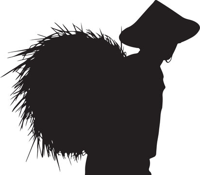 Silhouette of a person carrying a large bundle of straw reeds