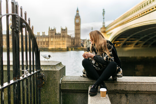 UK, London, young woman taking a snack near Westminster Bridge