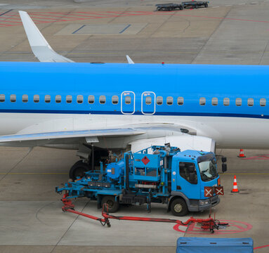 Blue commercial airplane being refueled by a truck in Amsterdam
