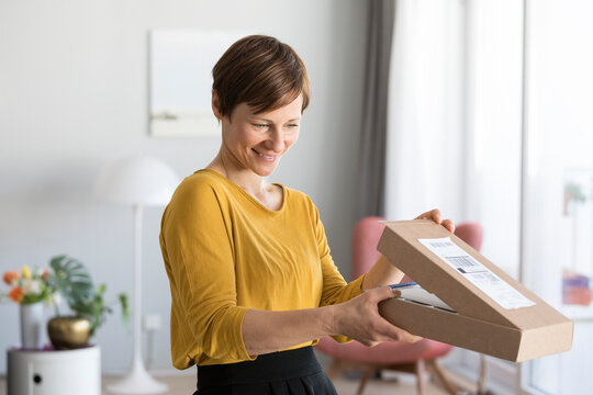Smiling woman unpacking parcel at home