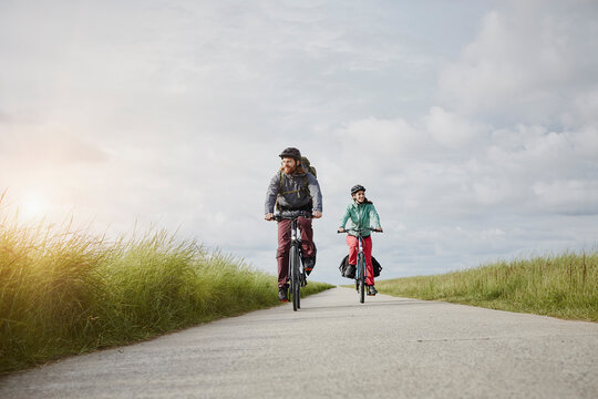 Germany, Schleswig-Holstein, Eiderstedt, couple riding bicycle on path through salt marsh
