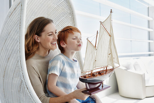 Happy mother and son with model sailing ship in hanging chair