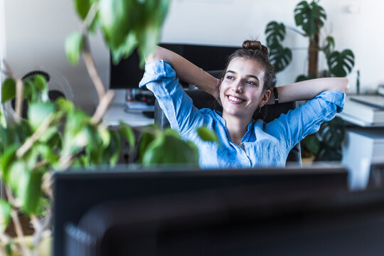 Smiling businesswoman relaxing at desk in the office