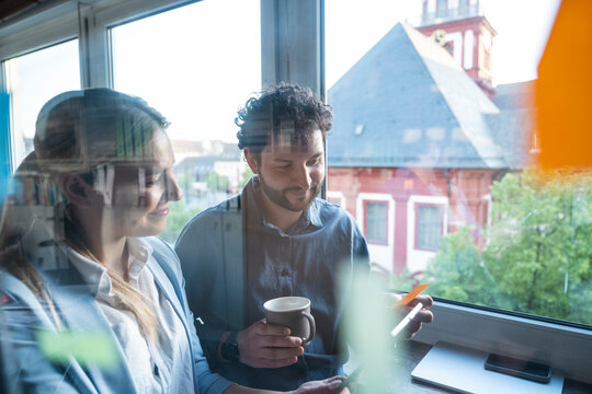 Colleagues brainstorming with postits on an office window