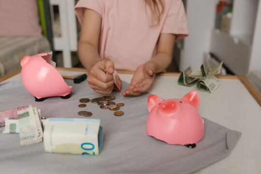 Hands counting money from a broken piggy bank indoors