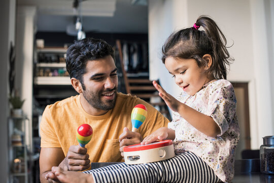 Father and daughter playing music in kitchen