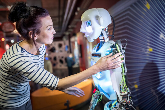 Technician gesturing near human robot in workshop