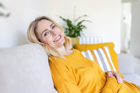 Smiling mature woman sitting on sofa at home