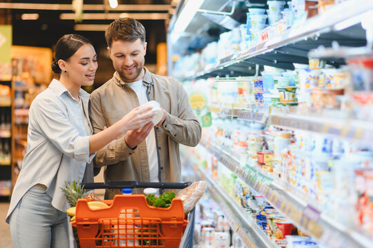 Couple shopping for groceries, choosing dairy products in supermarket