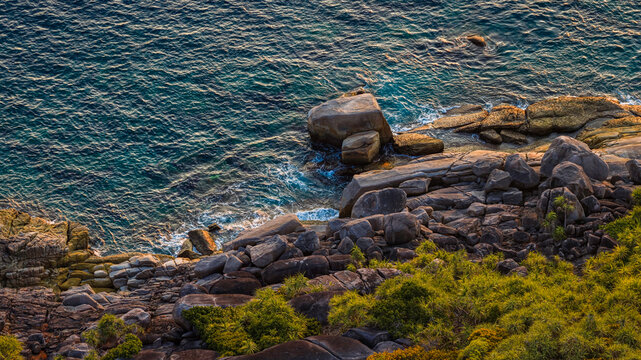 Aerial View of Rocky Coastline with Turquoise Waters crashing a Rugged Rocks Background