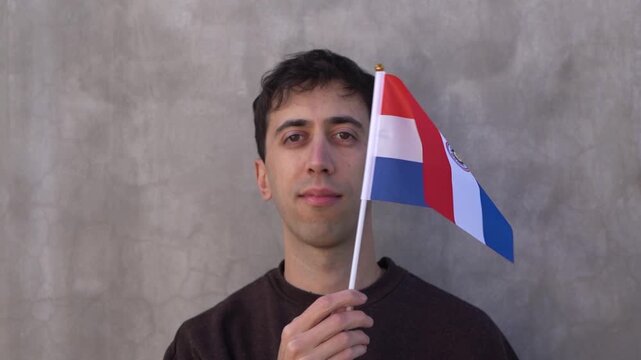 Close up shot of a man waving Paraguayan flag in slow motion. Paraguay country flag.